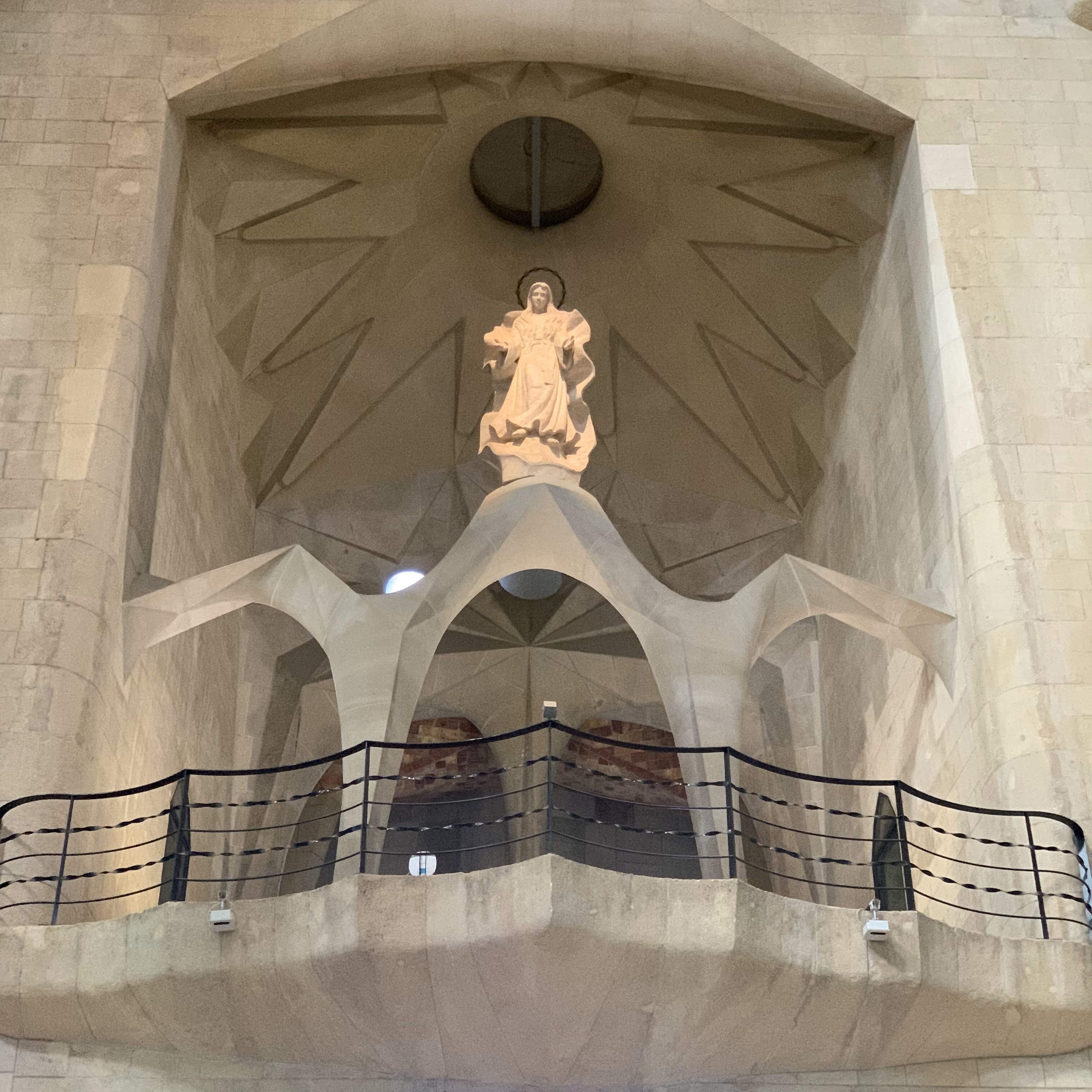 religious statue at the back of the building sitting atop of white balcony.